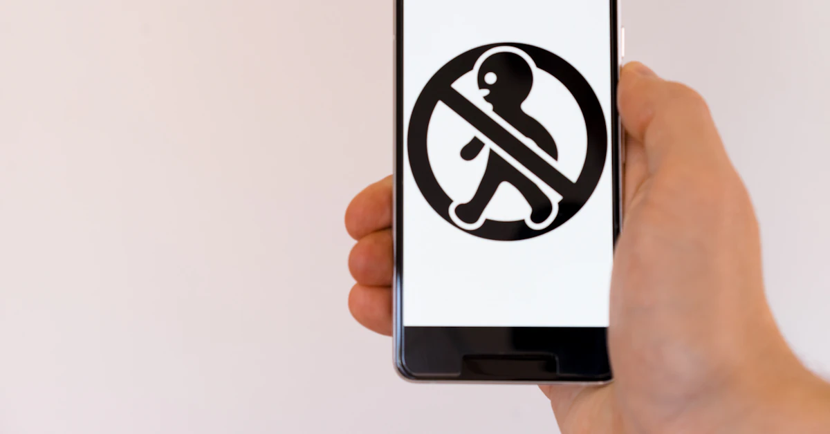 A hand holding a phone whose screen is filled by a large black prohibition sign.